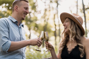 Elopement Photographer, a man and woman toast full champagne glasses in the forest