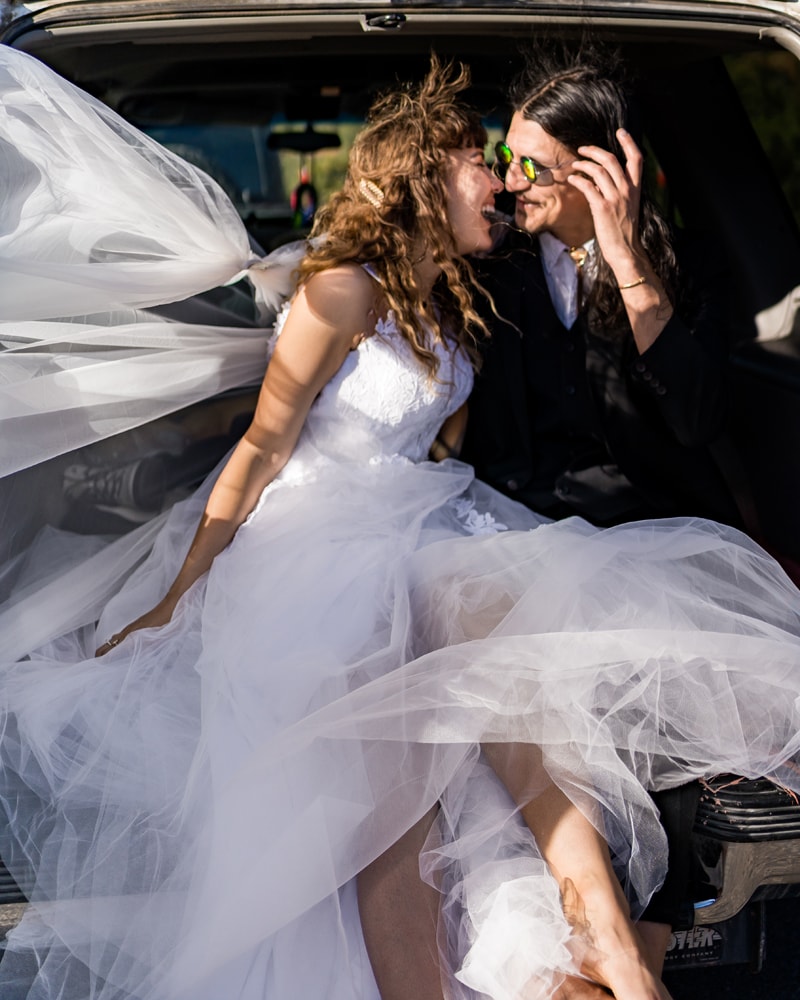 Wedding Photographer, a bride and groom embrace and lean in for kiss as they sit